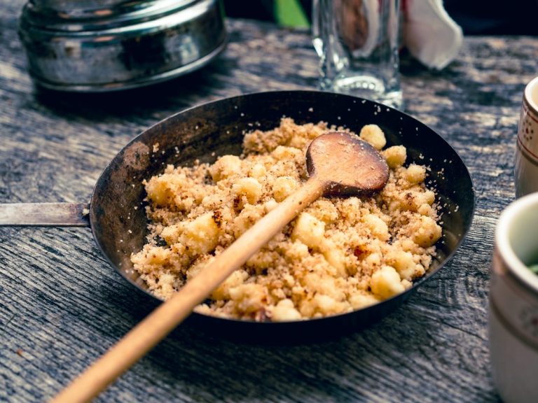Bellavista-Brand_Gastronomie Eine Schüssel mit Vorarlberger Spezialität und einer Holzlöffel auf einem Holztisch.