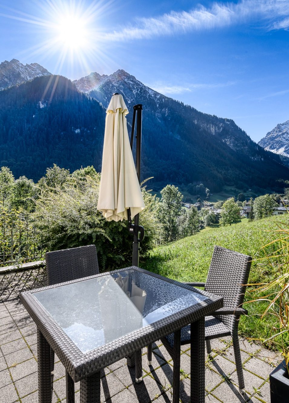 Bellavista-Brand_Aussicht Terrasse Ein Tisch mit Stühlen auf einer Terrasse mit Blick auf Berg Scesaplana, Vorarlberg und Sonnenschein.